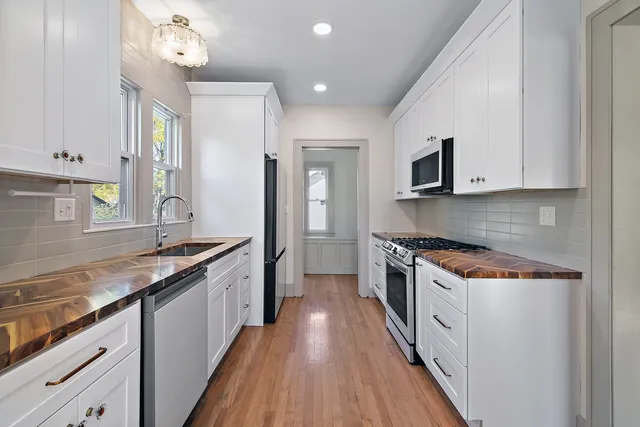 a kitchen with granite countertop a sink a counter top space stainless steel appliances and cabinets