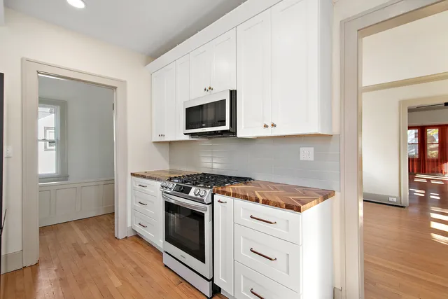 a kitchen with stainless steel appliances white cabinets and a stove top oven