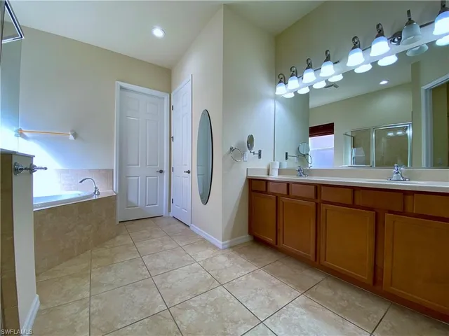 a spacious bathroom with a tub mirror and sink