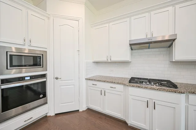 a kitchen with granite countertop white cabinets and stainless steel appliances