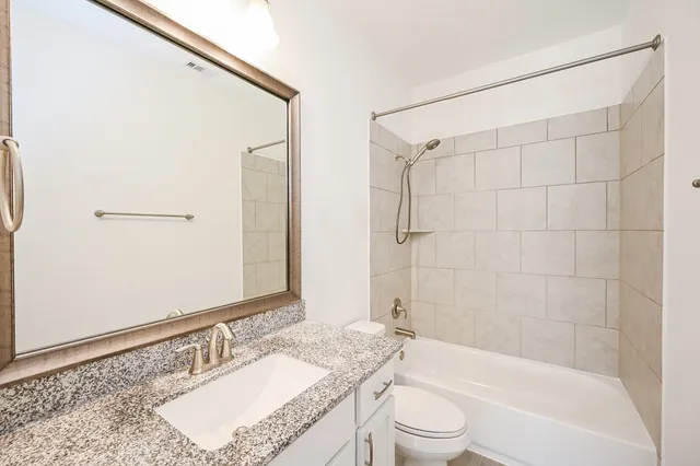 a bathroom with a granite countertop sink a toilet and shower