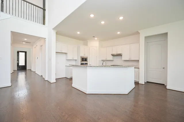 a view of kitchen with granite countertop white cabinets and stainless steel appliances
