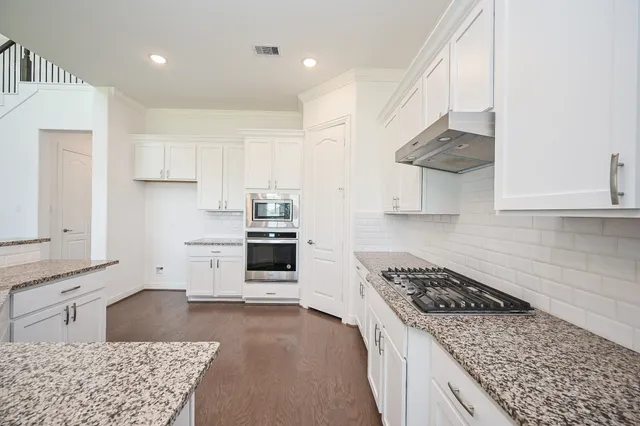a kitchen with stainless steel appliances granite countertop a stove a sink and a refrigerator