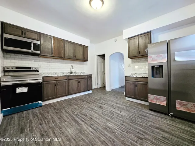 a kitchen with stainless steel appliances granite countertop a sink a stove top oven and refrigerator