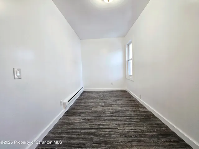 a view of a room with wooden floor and white walls