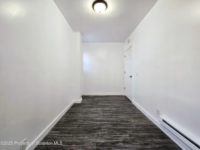 a view of an empty room with wooden floor