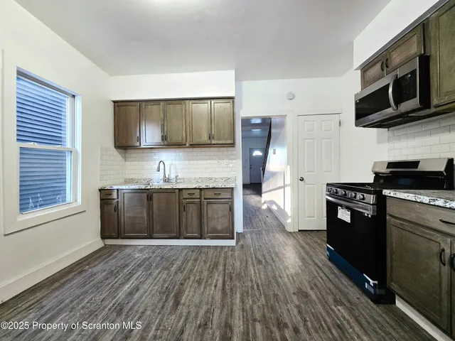 a kitchen with stainless steel appliances kitchen island granite countertop a stove a sink and a microwave