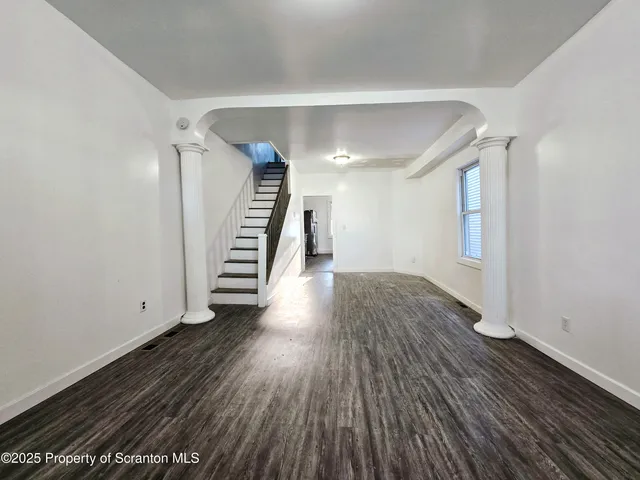 a view of a hallway with wooden floor and stairs
