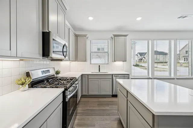 a kitchen with stainless steel appliances granite countertop a sink stove and cabinets