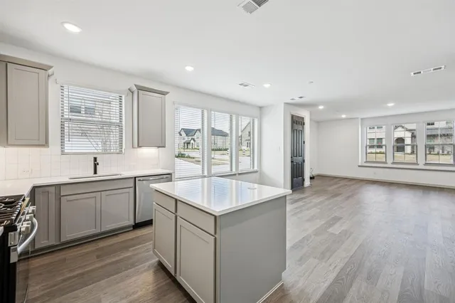 a large white kitchen with sink and dishwasher with wooden floor