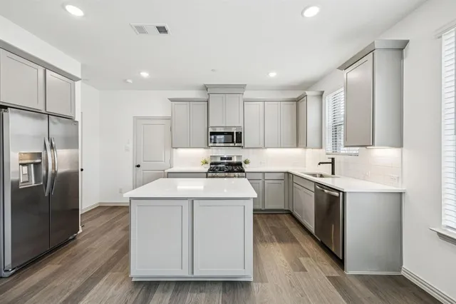 a kitchen with a sink stainless steel appliances and wooden floor