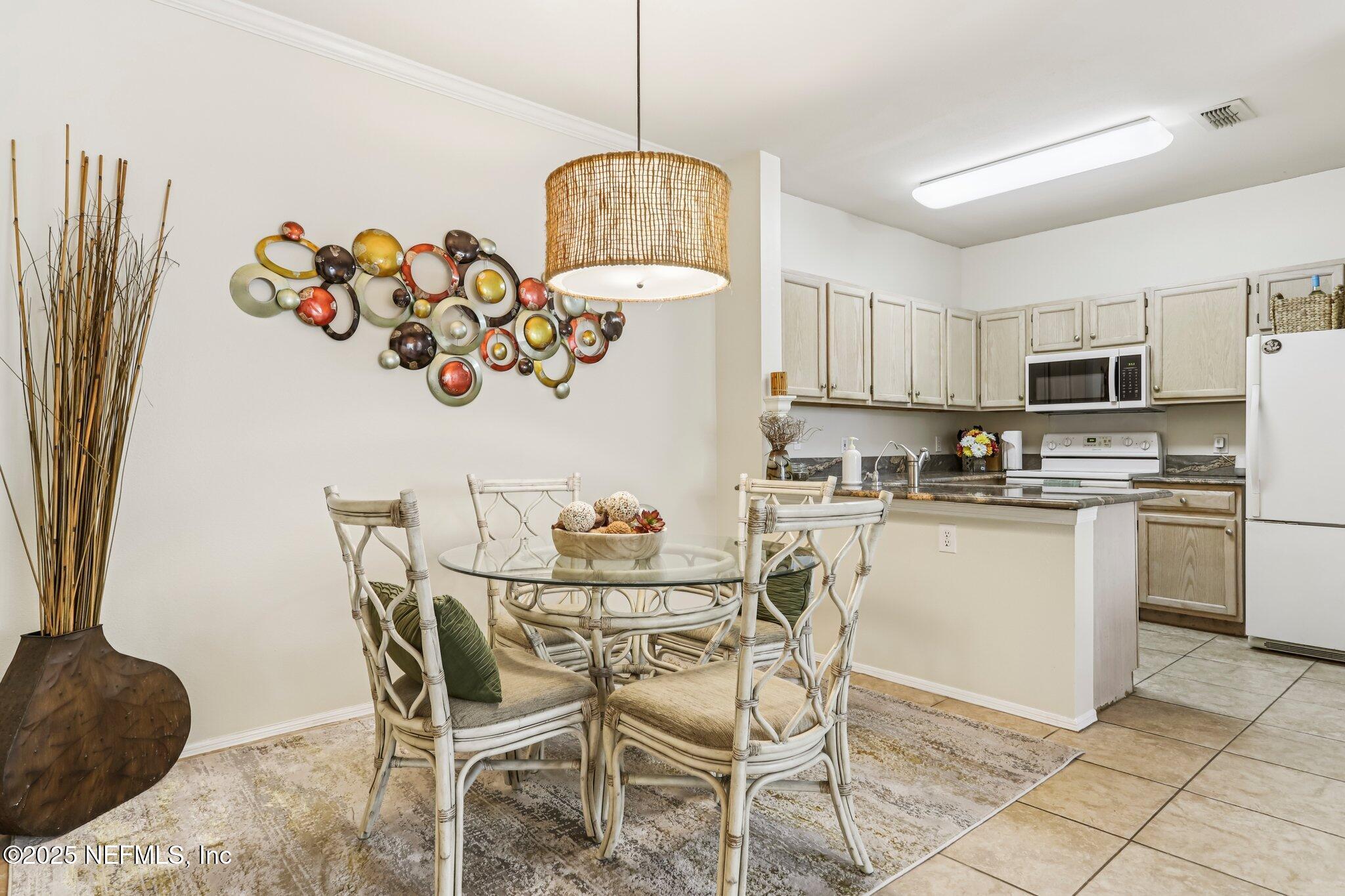 201 Colima Court, Unit 1221 Ponte Vedra Beach, FL 32082 - Photo 15 of 50 a kitchen with stainless steel appliances granite countertop a dining table chairs a refrigerator sink and microwave