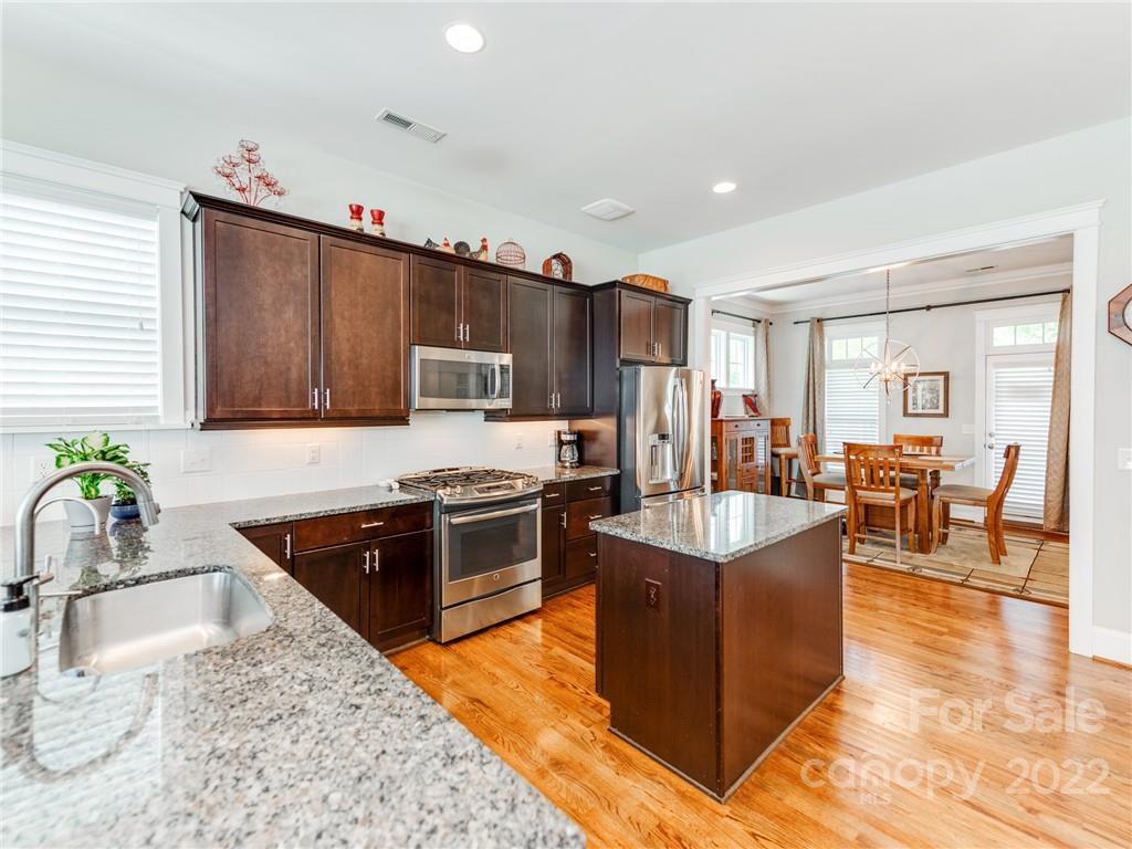 326 Mariemont Way Rock Hill, SC 29730 - Photo 11 of 36 a kitchen with stainless steel appliances granite countertop a stove top oven a sink dishwasher a dining table and chairs with wooden floor