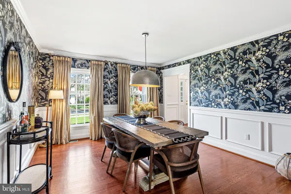 a dining room with wooden floor a chandelier a wooden table and chairs
