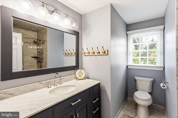 a bathroom with a granite countertop sink toilet and mirror