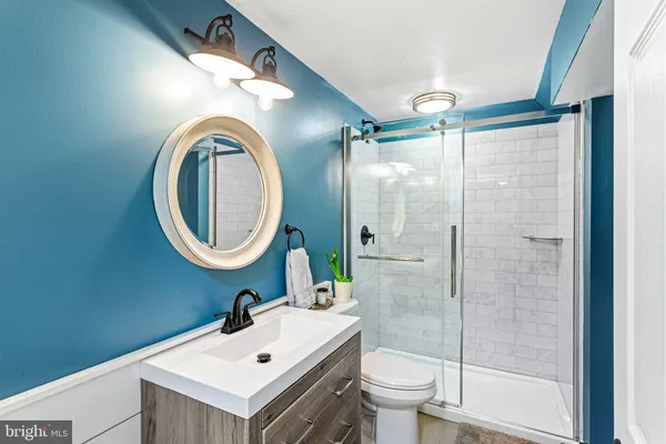 a bathroom with a granite countertop sink toilet a mirror and shower