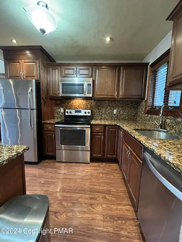 a kitchen with stainless steel appliances granite countertop a stove a sink and a microwave