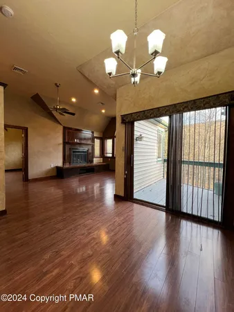 a view of a big room with wooden floor and windows