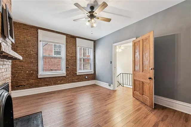a view of an empty room with wooden floor and a fireplace