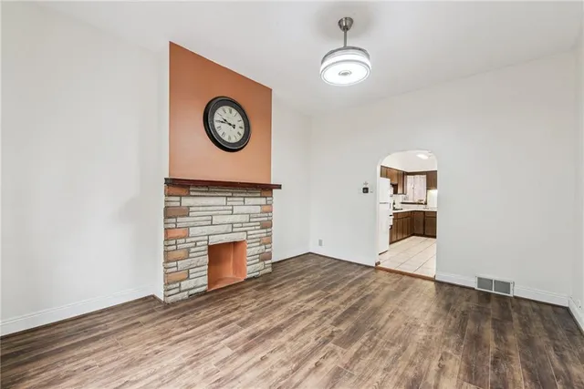 an empty room with wooden floor and a clock