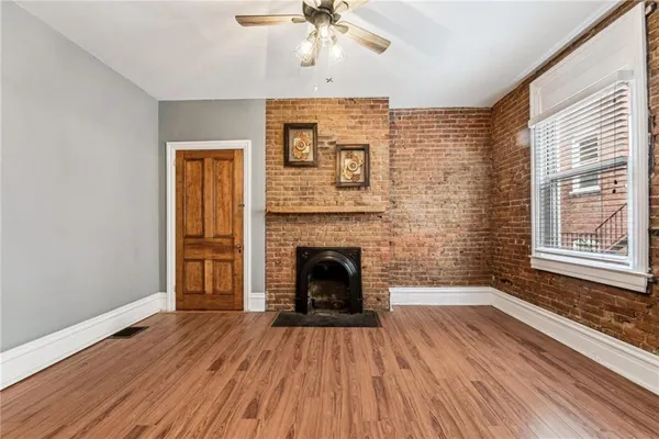 a view of an empty room with window and wooden floor