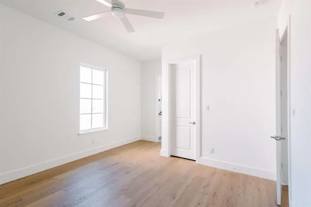 an empty room with wooden floor closet and windows