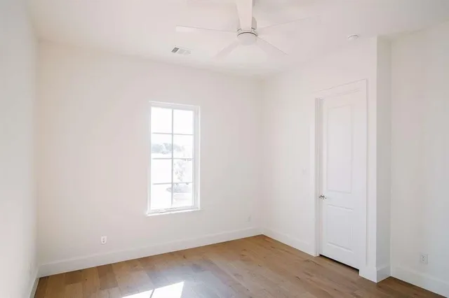 an empty room with wooden floor closet and windows