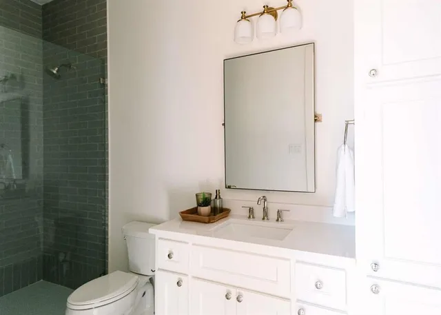 a bathroom with a sink vanity granite toilet and a mirror