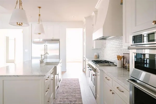 a kitchen with stainless steel appliances granite countertop a sink a stove and a refrigerator