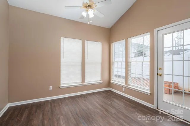 an empty room with wooden floor fan and windows