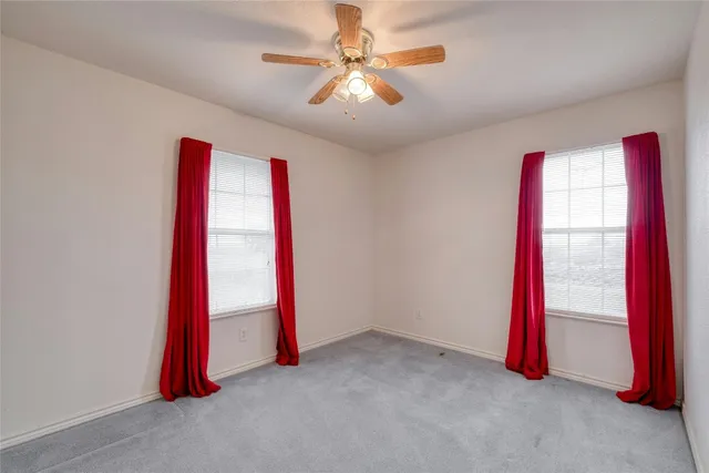an empty room with a flat screen tv and a ceiling fan
