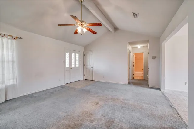 an empty room with windows and chandelier fan