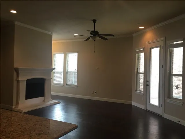 an empty room with wooden floor fireplace and windows