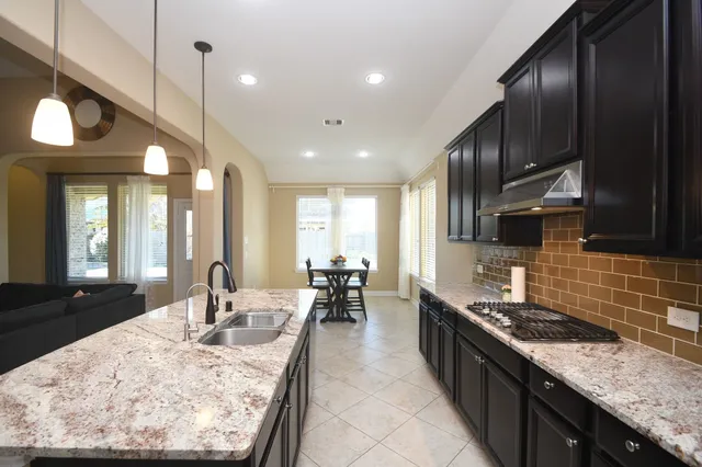 a kitchen with granite countertop stainless steel appliances a sink a stove and refrigerator