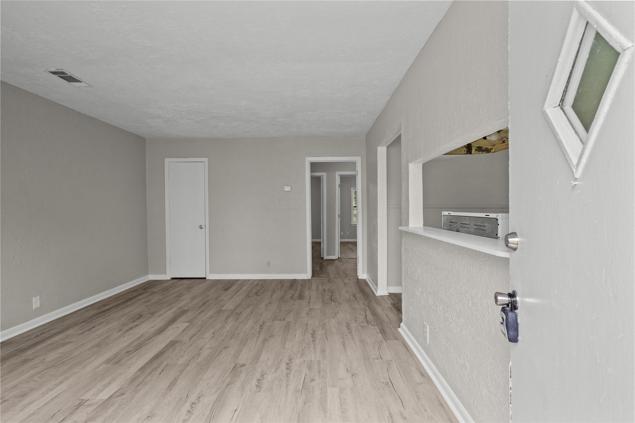 a view of a hallway with wooden floor and a bathroom