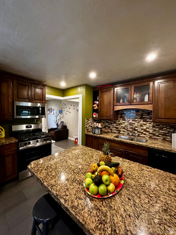 1931 Harrison Boulevard Ogden, UT 84401 - Photo 4 of 21 Kitchen featuring a large island with a stone-finish countertop, wood cabinetry, a stainless steel gas range, a stainless steel microwave, and a mosaic tile backsplash