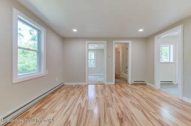 a view of empty room with wooden floor and fan