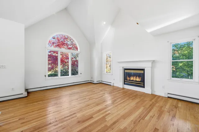 an empty room with window fireplace and wooden floor
