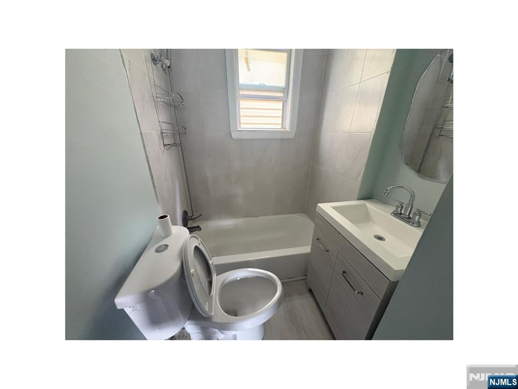 93 Highland Street, Unit 2 Paterson, NJ 07524 - Photo 8 of 9 a bathroom with a sink mirror vanity and bathtub