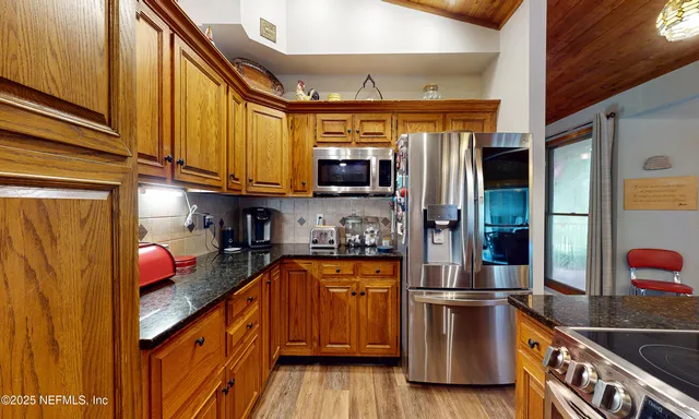 a kitchen with stainless steel appliances granite countertop a refrigerator and a stove top oven