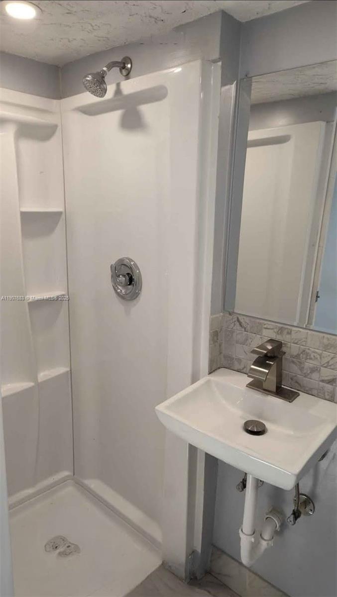 173 West 16th Street, Unit B Riviera Beach, FL 33404 - Photo 4 of 10 a bathroom with a sink a mirror and shower