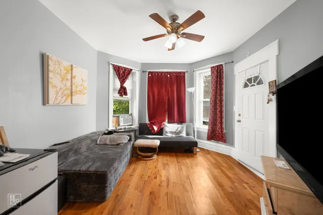 a living room with stainless steel appliances granite countertop a couch wooden floor and a window