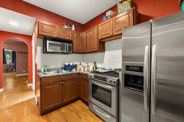 a kitchen with stainless steel appliances kitchen island granite countertop a refrigerator stove and sink