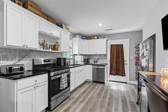 a kitchen with granite countertop a refrigerator stove top oven and sink