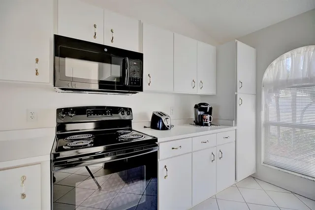 a kitchen with white cabinets and black appliances