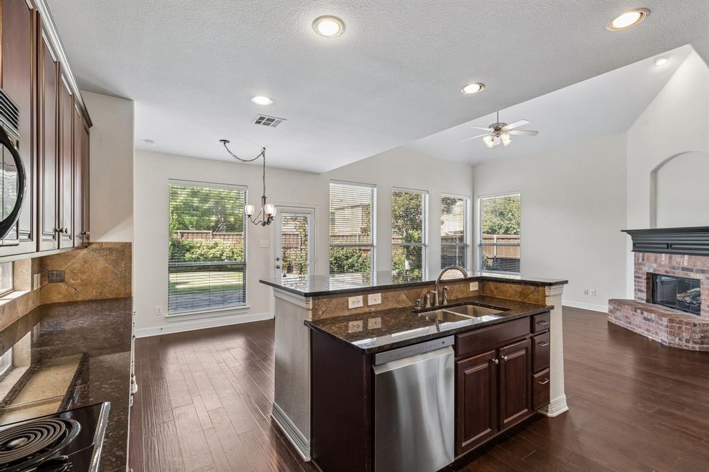 960 Remuda Road Frisco, TX 75033 - Photo 8 of 39 Kitchen with dark wood-finish cabinetry, built-in stainless steel appliances, and a central island featuring an undermount sink