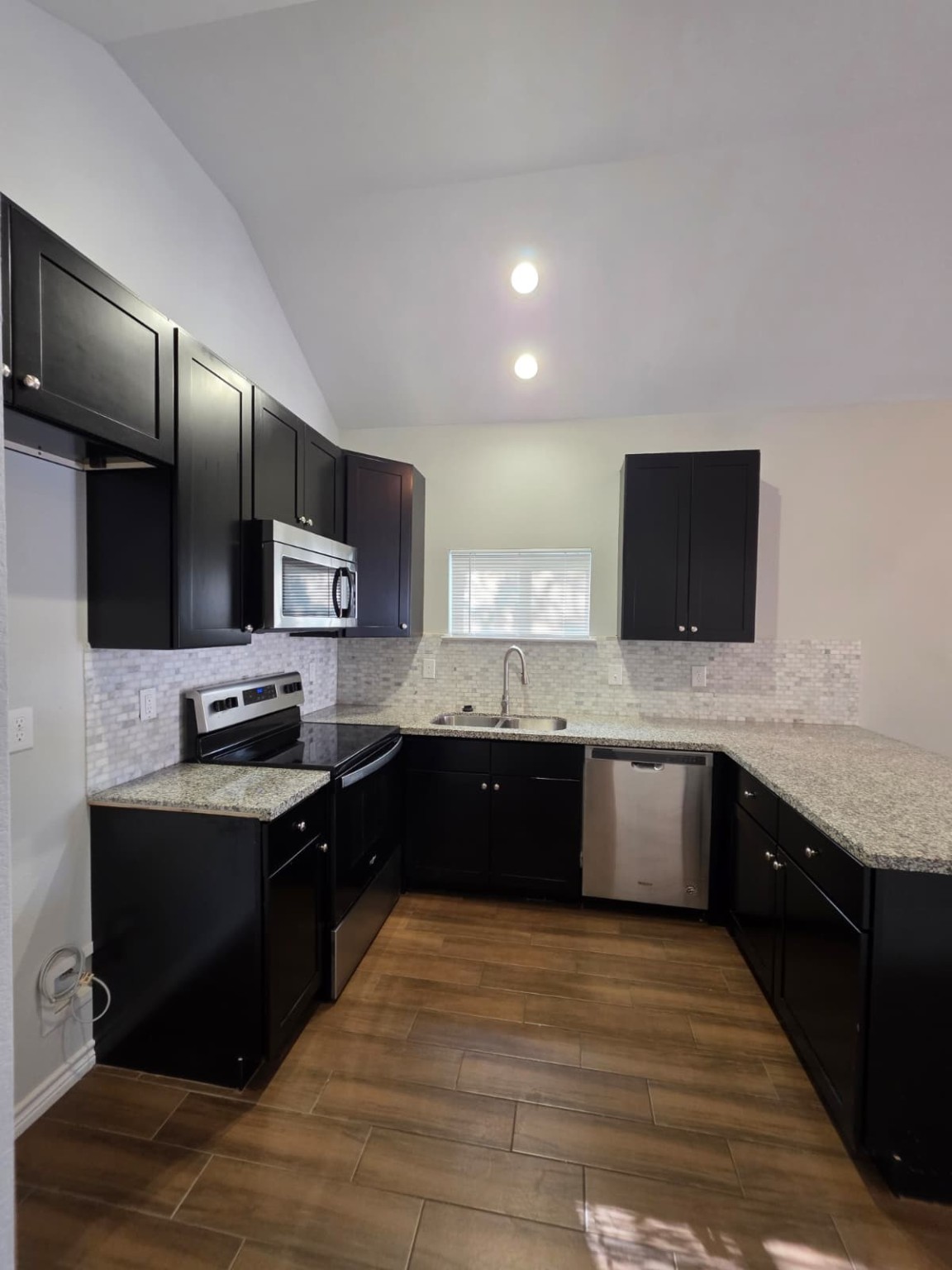 16338 Eastchase Street Montgomery, TX 77316 - Photo 3 of 12 a large kitchen with stainless steel appliances kitchen island granite countertop a sink counter space and cabinets