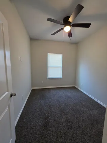 an empty room with a chandelier fan and windows