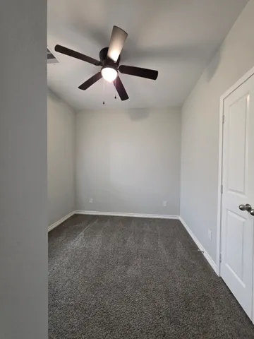 an empty room with a ceiling fan and a window