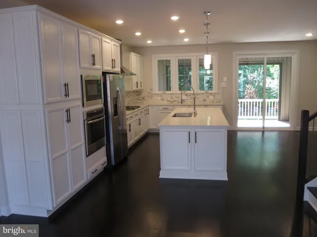 a kitchen with kitchen island granite countertop a sink stove and refrigerator